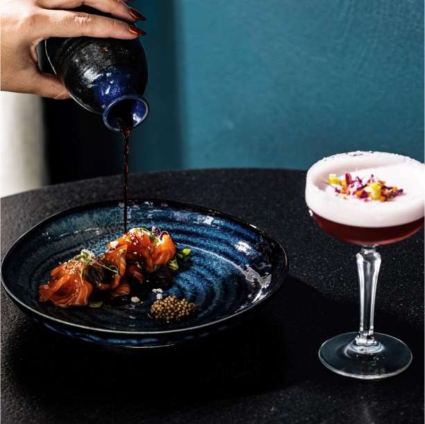 A cosmopolitan dinner setting with sashimi and cocktail