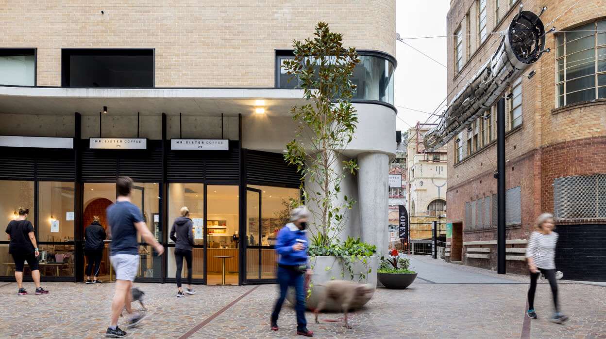 People bustling by Lyrique Lane shopfronts, with the laneway entrance to the right